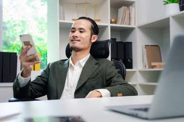 Obraz na płótnie Canvas Asian businessman use cellphone and smile in the office 