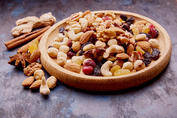 Aesthetic wooden bowl with assorted nuts, raisins and cranberries from above on rustic background....