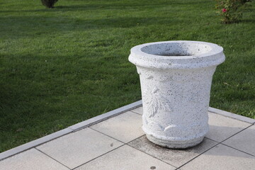 Naklejka premium stone flowerpot on the lawn in the city park, closeup of photo