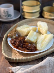 Ubi rebus or steam cassava is traditional malay dish. Serve with fried chili sambal over dark background. Selective focus.
