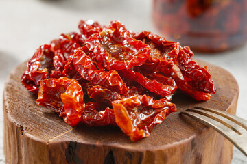 Close-up of homemade sun-dried tomatoes on a wooden board. Studio shot. - obrazy, fototapety, plakaty
