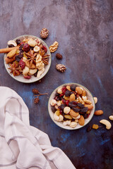 Aesthetic saucers with mixed nuts. Healthy desserts and snacks. Walnuts, almonds, hazelnuts and cashews. Raisins and cranberries on rustic background.