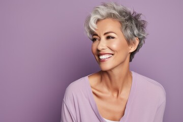 Perfect smile. Beautiful mature woman looking at camera and smiling while standing against purple...