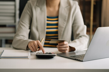 Business woman calculating monthly office expenses, taxes, bank account balance and credit card bills payment, Income is not enough for expenses in office.