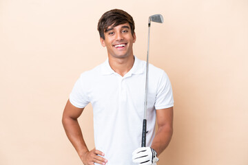Young golfer player man isolated on ocher background posing with arms at hip and smiling