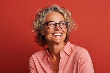 Portrait of happy mature woman in eyeglasses on red background - obrazy, fototapety, plakaty