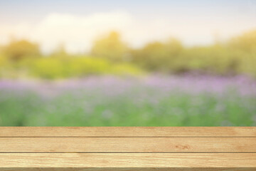 Fototapeta premium Empty wooden table top or counter blur flowers garden nature background in green trees spring park sunlight sky for template mock up and display montages product. Wood table plank background
