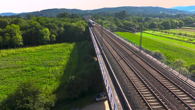 Railroad With Train Traveling On Tracks Over Green Rural Landscape In Padr&oacute;n, Rois A Coru&ntilde;a, Spain. Wide Shot