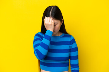 Young Chinese woman isolated on yellow background with headache