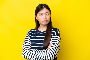 Young Chinese woman isolated on yellow background keeping the arms crossed