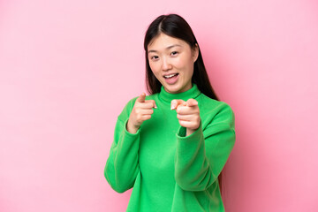 Young Chinese woman isolated on pink background surprised and pointing front