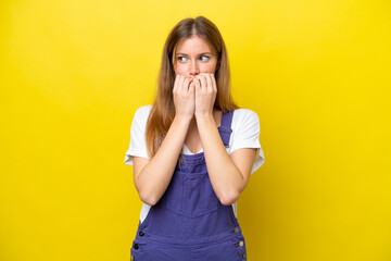 Young caucasian woman isolated on yellow background nervous and scared putting hands to mouth