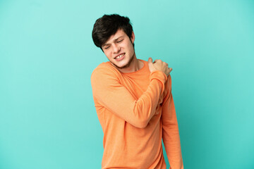 Young Russian man isolated on blue background suffering from pain in shoulder for having made an...