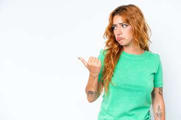 Young caucasian woman isolated on white background unhappy and pointing to the side