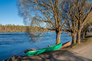 View of Vuoksi river and river banks in spring, trees, boat and water, Mellonlahti, Imatra, Finland