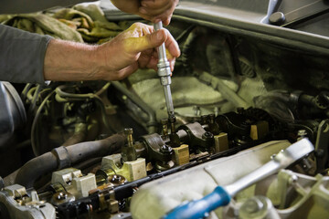 hands of mechanic screwing or unscrewing rocker arm shaft of combustion engine in old SUV