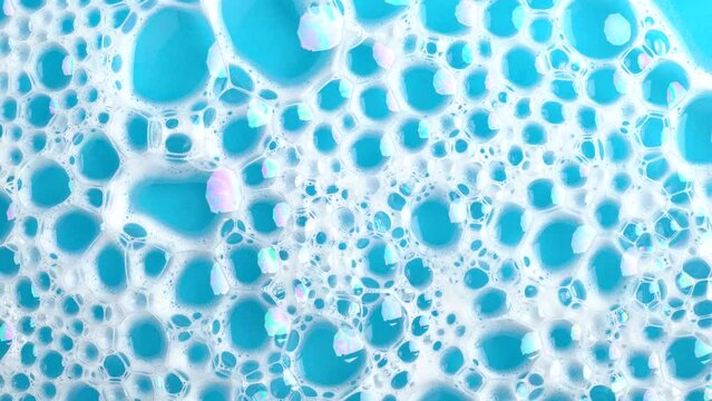 Soapsuds bubbles on blue water. Soap foam. Background of dusty foam with bubbles. Soap sud in motion