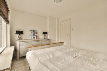 a bedroom with a bed, dresser and mirror in the corner room on the left is a window to the right
