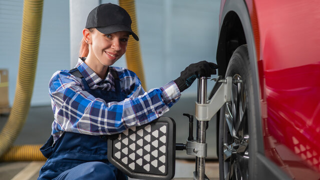 A female auto mechanic makes a camber. Woman working in a car service.