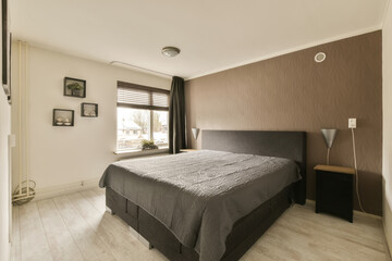 a bedroom with brown walls and white flooring, there is a large bed in the room has a black headboard on it