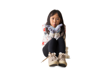 Portrait of attractive cheerful Asian little girl sending air kisses sitting on floor festal Christmas day December winter, full body, isolated on white and transparent background