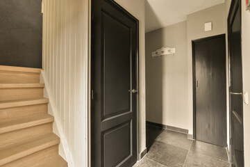 a hallway with black doors and wooden steps leading up to the second floor in an apartment or...