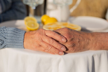 An elderly couple is holding hands at the table
