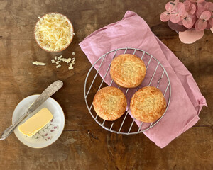 Spelt flour cheese scones on a pink cloth on top of an old wooden table, with a lilac and pink...