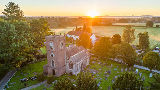 Old church at sunrise in summer from above in small English village