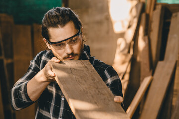 Joiner furniture maker worker choice select wood material from pile stock to find wood piece that...