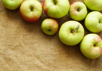 Apples lie on the cloth burlap. Autumn fruit harvest on a textural beige background. Delicious juicy healthy fruit. Mock up with Empty space for text