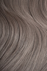 Blond hair close-up as a background. Women's long light brown hair. Beautifully styled wavy shiny curls. Hair coloring. Hairdressing procedures, extension.