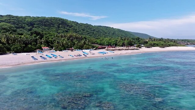 Aerial view of beautiful sandy beach, clear Caribbean sea water with coral reef and green mountains in background - Barahona, Dominican Republic 