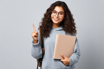 Naklejka premium College girl holding books in hand and showing finger on up side.