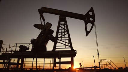 oil production. silhouette oil and gas production rig at sunset glare. oilfield business lifestyle...