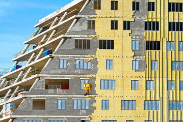 Building construction, windows installing, insulation and cladding facade wall. Thermal insulation of external wall with stone wool. Warming facade of multistory building. Ventilated facade insulation