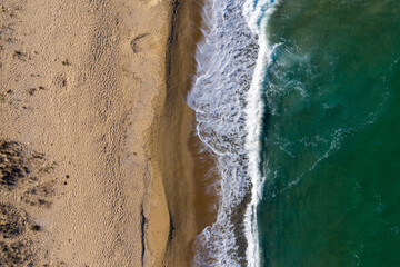 Fototapeta na wymiar Aerial view of ocean waves washing a sandy shoreline