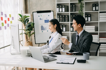 Two business workers talking on the smartphone and using laptop at the office.