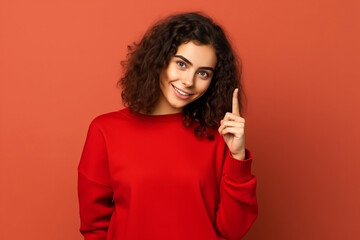 A 17 years old girl on a red background gesticulates with her index finger, copy space