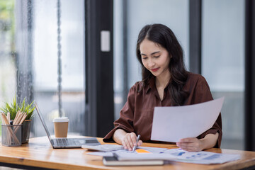 Young attractive business asian woman checking searching document her project with laptop computer in the office room.