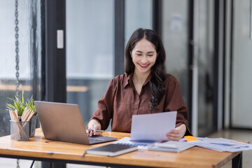Young attractive business asian woman checking searching document  her project with laptop computer in the office room.