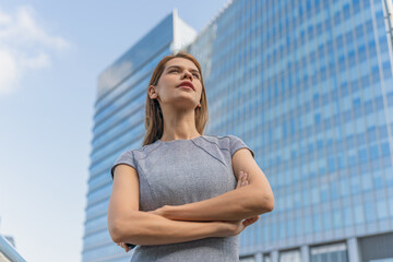 Portrait of a young and successful white caucasian business woman standing in front of a modern cityscape of office buildings