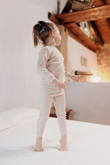 Child's Bedtime Joy: Playful 4-Year-Old Jumping for Joy in Pajamas at Cozy Rustic Home.