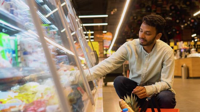 Side view of handsome indian man buying cheese. A man shopping cheese in grocery store