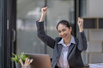 Happy excited successful Asian businesswoman triumphing with document  laptop computer in the workplace office and copy space