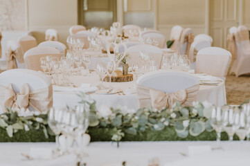 Tables decorated in white and cream for a wedding and chairs with cream or beige bows
