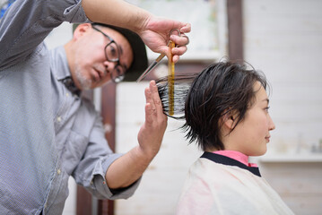 女性の髪をカットする美容師の手元のクローズアップ
