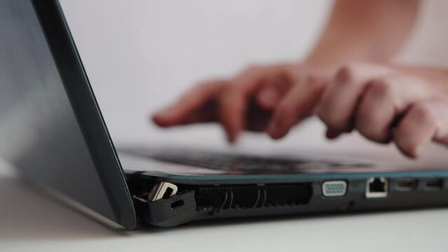 A man types on the keyboard of a broken laptop. Broken laptop case hinge, close-up