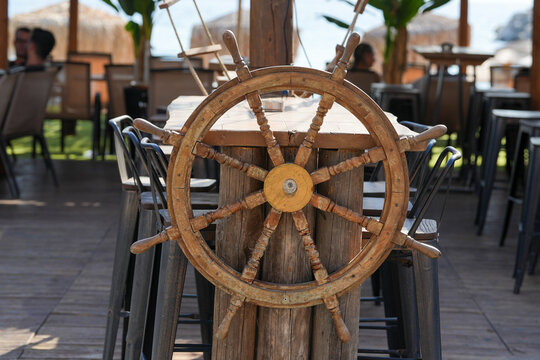 the rudder of a maritime vessel placed on the terrace of a bar on the beach. detail.