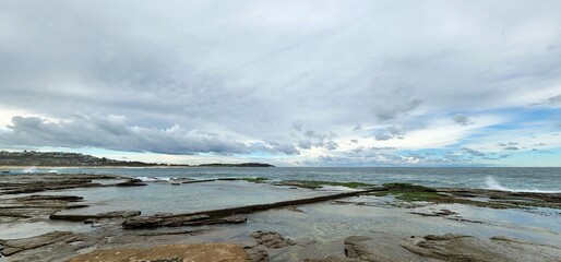 Natural seaside scene, view of the sea in a rocky seaside in Dee Why Beach, Sydney. Rocks in the shallow water near the coastline.